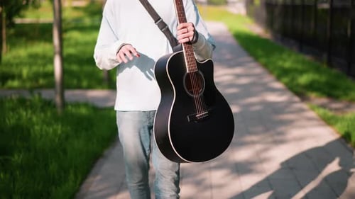 Musician Walking Outdoors Casual Musician Carrying Guitar Along Bright City Park Trail Relaxed