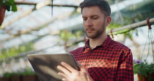 Gardener Using Digital Tablet in Greenhouse