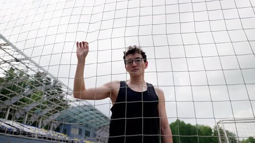 a Guy in a Sports Uniform and Glasses Looks at the Camera Smooth Movement of the Camera Bottom View