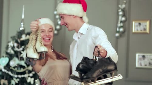 Joyful Couple in Festive Hats Embracing By a Christmas Tree with Skates