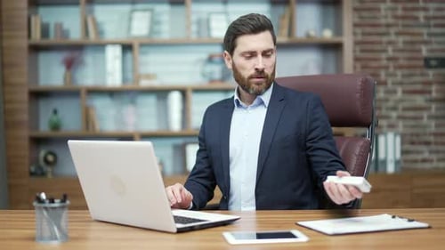 Busy mature bearded business man entrepreneur working typing on laptop and turn on remote control ch