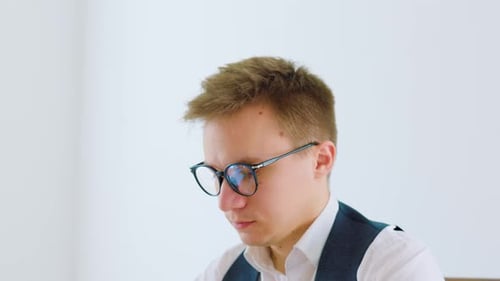 A Stylish Young Businessman Dressed in a Whitecollar Shirt and Tie Sits at His Modern Home Office