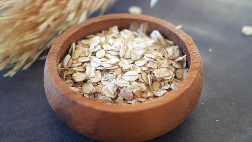 Slow Motion of Falling Roasted Oats Flakes in a Wooden Bowl