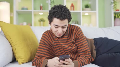 Young Adult Relaxing Using Smartphone on Couch