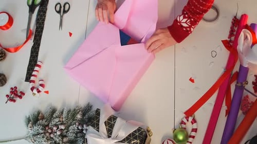 Wrapping Christmas Present with Pink Paper at Table