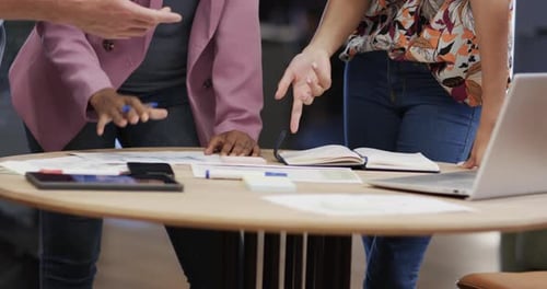 Section intermédiaire de collègues masculins et féminins de divers horizons discutant au bureau à l'aide d'une tablette, au ralenti