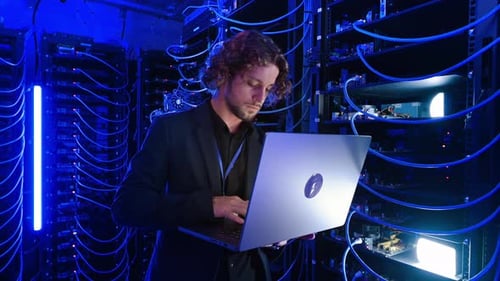IT Engineer Using Laptop in Blue Server Room