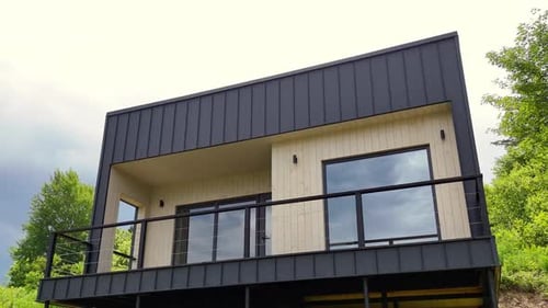 Modern Cubic Minimalist House Exterior with Dark Metal Siding and Large Glass Windows Overlooking a
