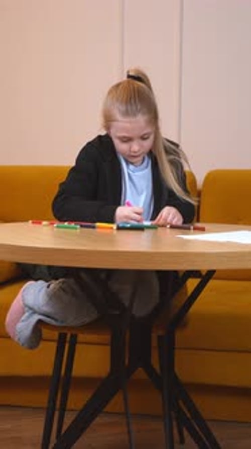 Girl Drawing at a Table with Markers in Home