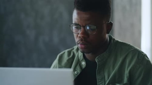 At a Local Cafe an African American Businessman is Deeply Focused on His Laptop Contemplating