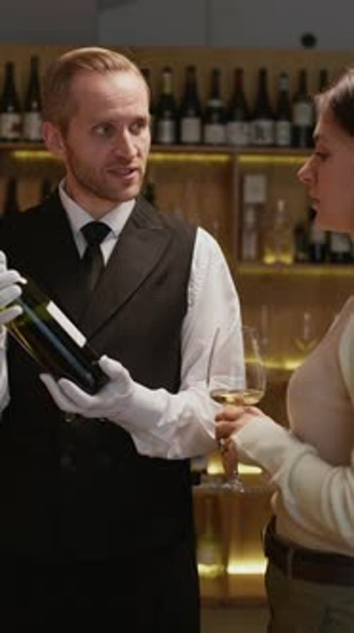 Sommelier Helping to Choose Wine to Female Customer in Beverage Store