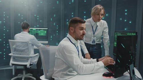 Colleagues coding data at computers in server room