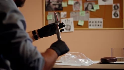 Closeup Detective's Office Middleaged Investigator in Shirt and Tie Sitting Desk Examining Evidence