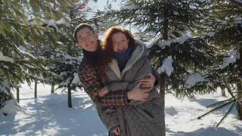 Ein Ehepaar umarmt sich, während es mitten in einem verschneiten Park steht Ein Mann umarmt und küsst seinen