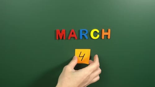Hand sticking a sticker 4 March calendar day on school board. 4 date of March. Fourth day March
