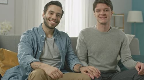 Affectionate Men Sitting Together Holding Hands on Sofa