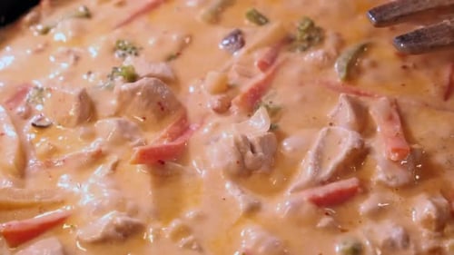 Creamy chicken curry meal bubbles, boils in saucepan on hot stovetop