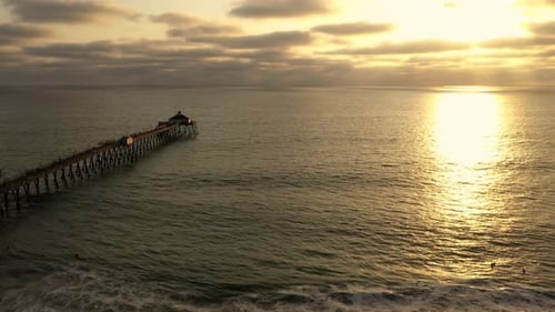 Sunlight on ocean surface with pier and surfers in water, Imperial Beach, California