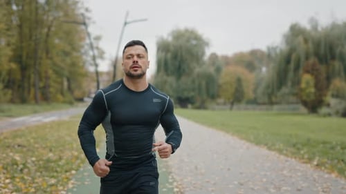 Sport Man Running in Autumn Park Male Runner Run in Park at Morning Young Man Training Run in Slow