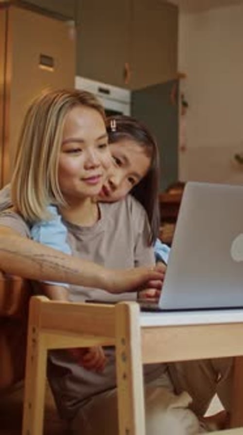 Mother and Daughter Using Laptop at Table Indoors