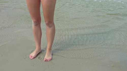 Static shot sportive long feminine legs standing at beach sea shore,slow motion