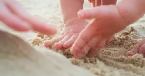 Sand games. Baby plays with sand on the beach, close up shot with hands in the frame