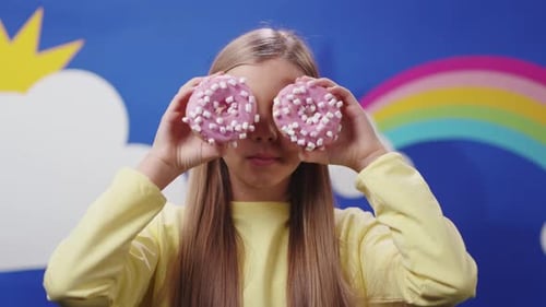 A Playful Girl Enjoying Delicious Donuts Surrounded By a Bright and Colorful Background