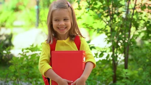 Little Student Girl Wih Book Looks at Camera and Laughs Schoolchild Education