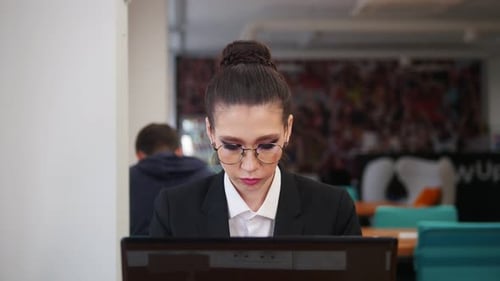 A Woman in Glasses Sitting in the Office and Working