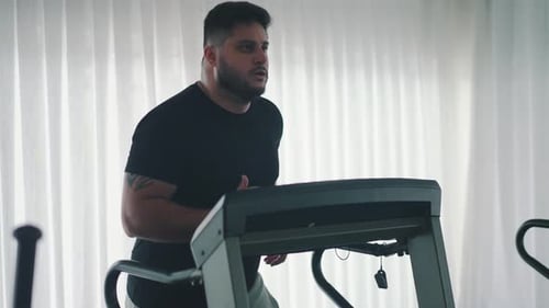 Jovem barbudo treinando em uma esteira, máquina, treino na academia, movimento em câmera lenta