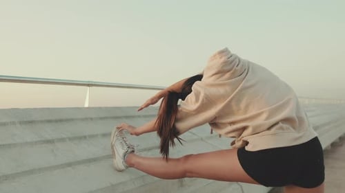 Woman Stretching Leg Against Concrete Wall Outdoors