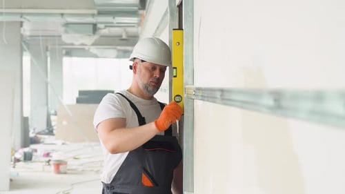 A Man Builder Measures of the Vertical Deviation of Plasterboard Wall Bubble Level Ruler