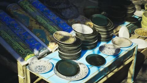 Traditional Ornate Plates and Rolled Carpets on Market Stall