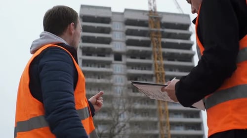 Construction engineers at the construction site are discussing the project of a high-rise building.