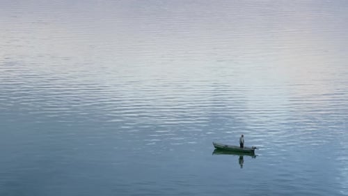 Fischer steht im Boot und beobachtet Flussflussdrohne. Glühende Wasseroberfläche