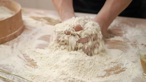 Hands Kneading Dough on Wood Surface Close Up