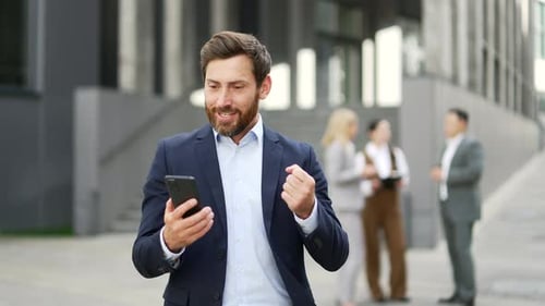 Excited Businessman Celebrates Success With Smartphone