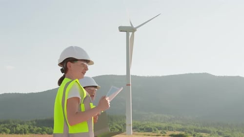 A Group of Engineers is Examining Wind Turbine Blueprints Outdoors Donning Highvisibility Vests and