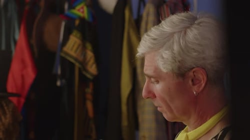 Person Touches Face in Front of Clothing Rack