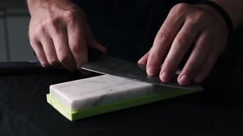 Male Hands Sharpening Kitchen Knife With Whetstone