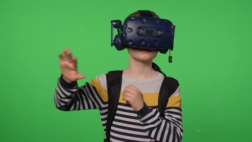 A Little Boy Uses a Virtual Reality Headset in a Studio with a Green Background
