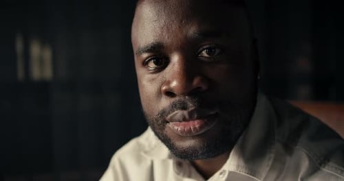 Closeup Portrait of a Blackskinned Man in a White Shirt Who Looks at the Camera and Does Not Smile