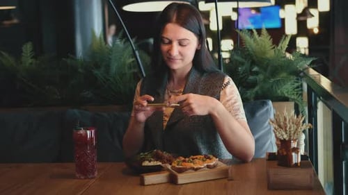 Woman Blogger Taking Pictures of Food in a Restaurant