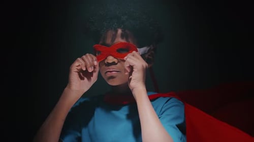 Portrait of Little Boy Putting on Superhero Mask and Posing in Studio