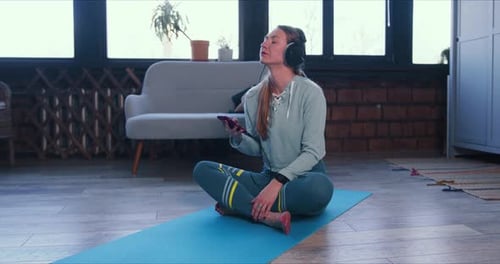 Woman Listening to Music on Yoga Mat at Home