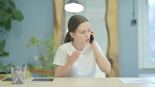 Frustrated Woman Talking on Phone at Desk
