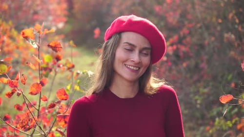 Young Beautiful Sensual Woman in a Red Sweater and Beret Posing in the Autumn Forest Against a
