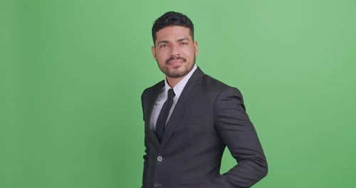 Portrait of handsome young Asian businessman in a black suit. Isolated on green background in studio