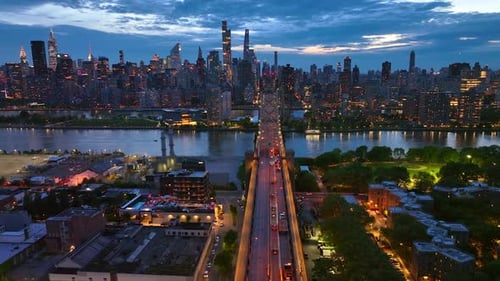 Stunning view of the city at coming evening. Queensboro Bridge in lights with cars passing along.