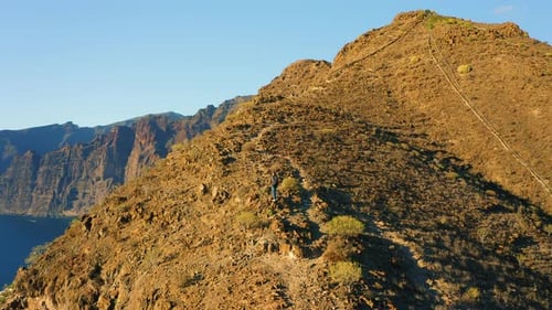 Aerial of a Man Silhouette Climbing Up the Mountain at Amazing Sunset